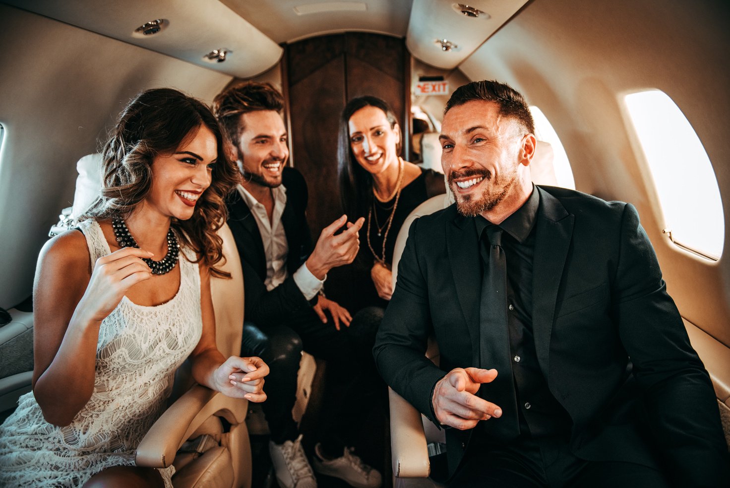 A group of rich people sitting side by side while traveling aboard a private airplane